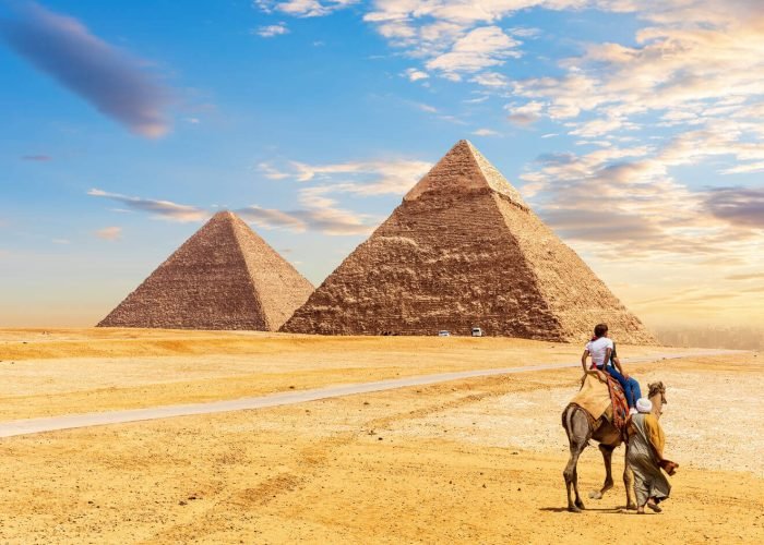 I Turisti Montano Un Cammello Di Fronte Alle Piramidi Di Giza